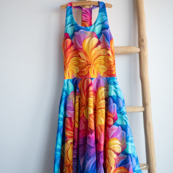 Zomerjurk voor kinderen, halterjurk met regenboogkleuren en zwierige cirkelrok, hangend op houten ladder met witte achtergrond