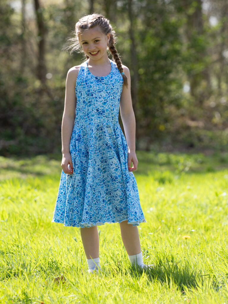 Zomerjurk kinderen met lichtblauwe mozaïek print gedragen door model, halterjurk met zwierige cirkelrok